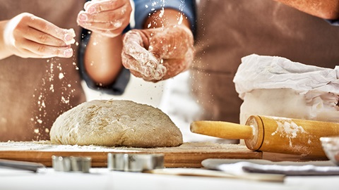 mani che buttano la farina su una pagnotta